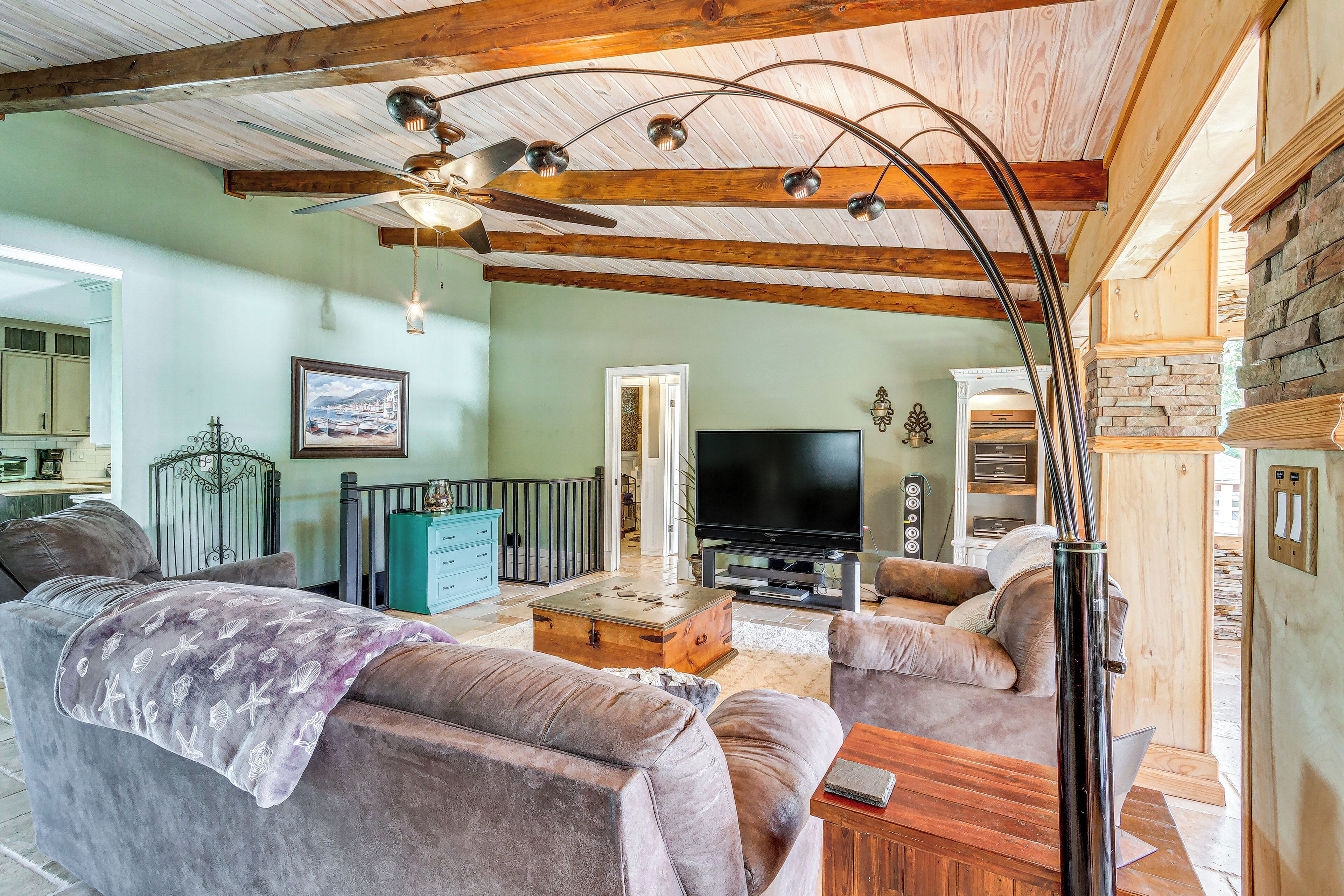 Een woonkamer met een houten plafond, een flatscreentelevisie en een open haard.