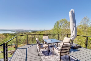 A deck with a table and chairs, overlooking a scenic landscape with a lake and hills. - Charming Edgemont Home w/ Deck & Lake Views! (Edgemont)