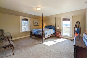 A four-poster bed with a blue and white bedspread, a wooden dresser, a chair, and a window with a view of the beach. - Charming Stevensville Home w/ Open Yard! (Stevensville)