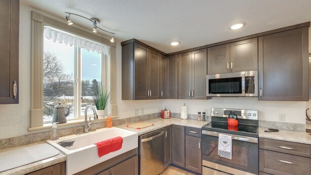 A modern kitchen with stainless steel appliances, a large window with a view, and wooden cabinets. - Charming Stevensville Home w/ Open Yard! (Stevensville)