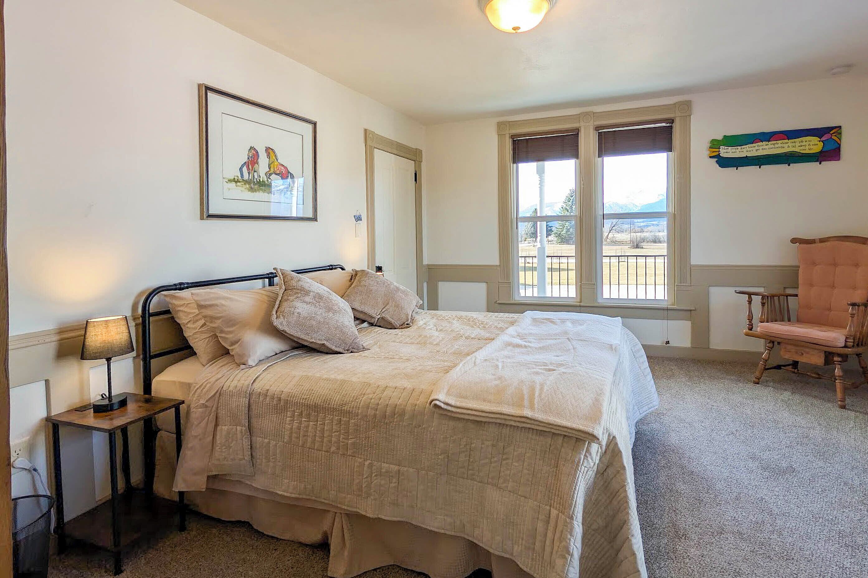 A bedroom with a bed, a chair, a window, and a picture on the wall.