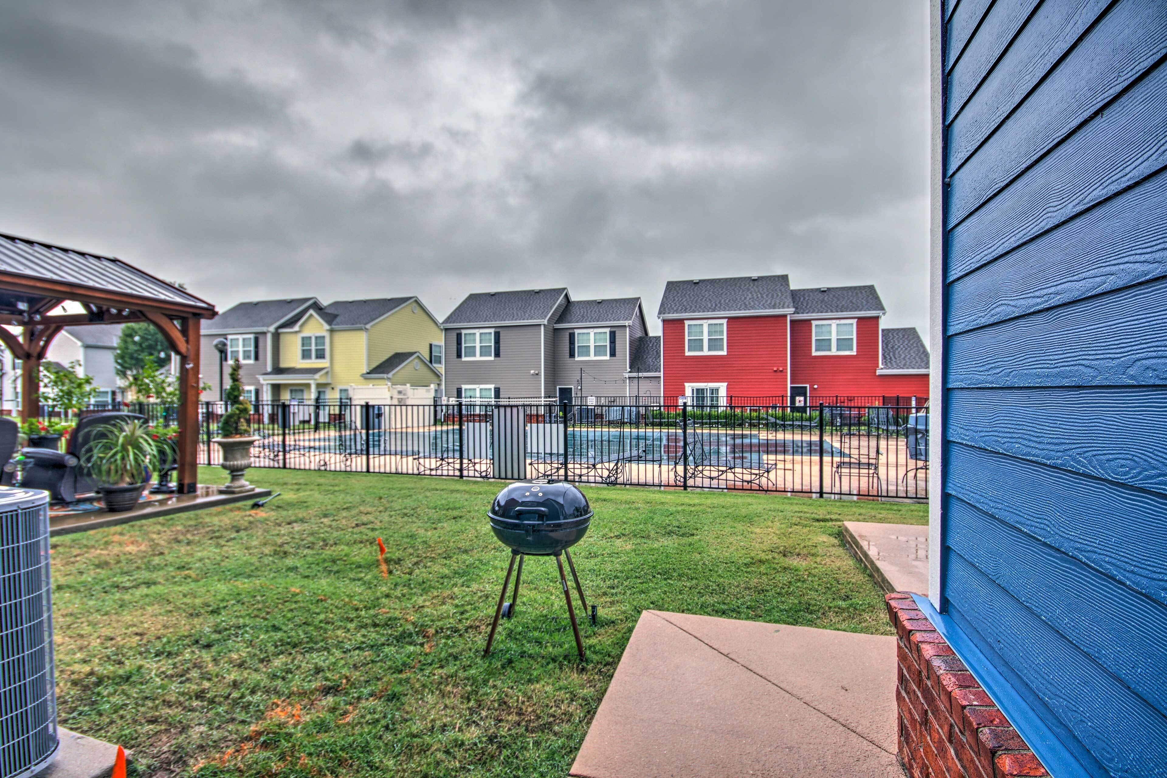 A backyard with a barbecue grill, a patio, and a view of colorful houses.
