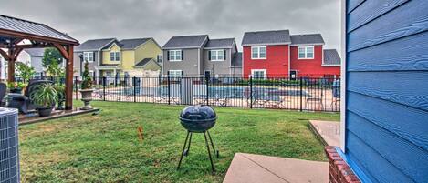 A backyard with a barbecue grill, a patio, and a view of colorful houses.