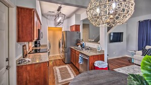 A modern kitchen with granite countertops, wooden cabinets, and stainless steel appliances. There is a dining area with a table and chairs, and a large decorative light fixture above the kitchen. - 1 Block to Boat Ramp: Monkey Island Home (Afton)