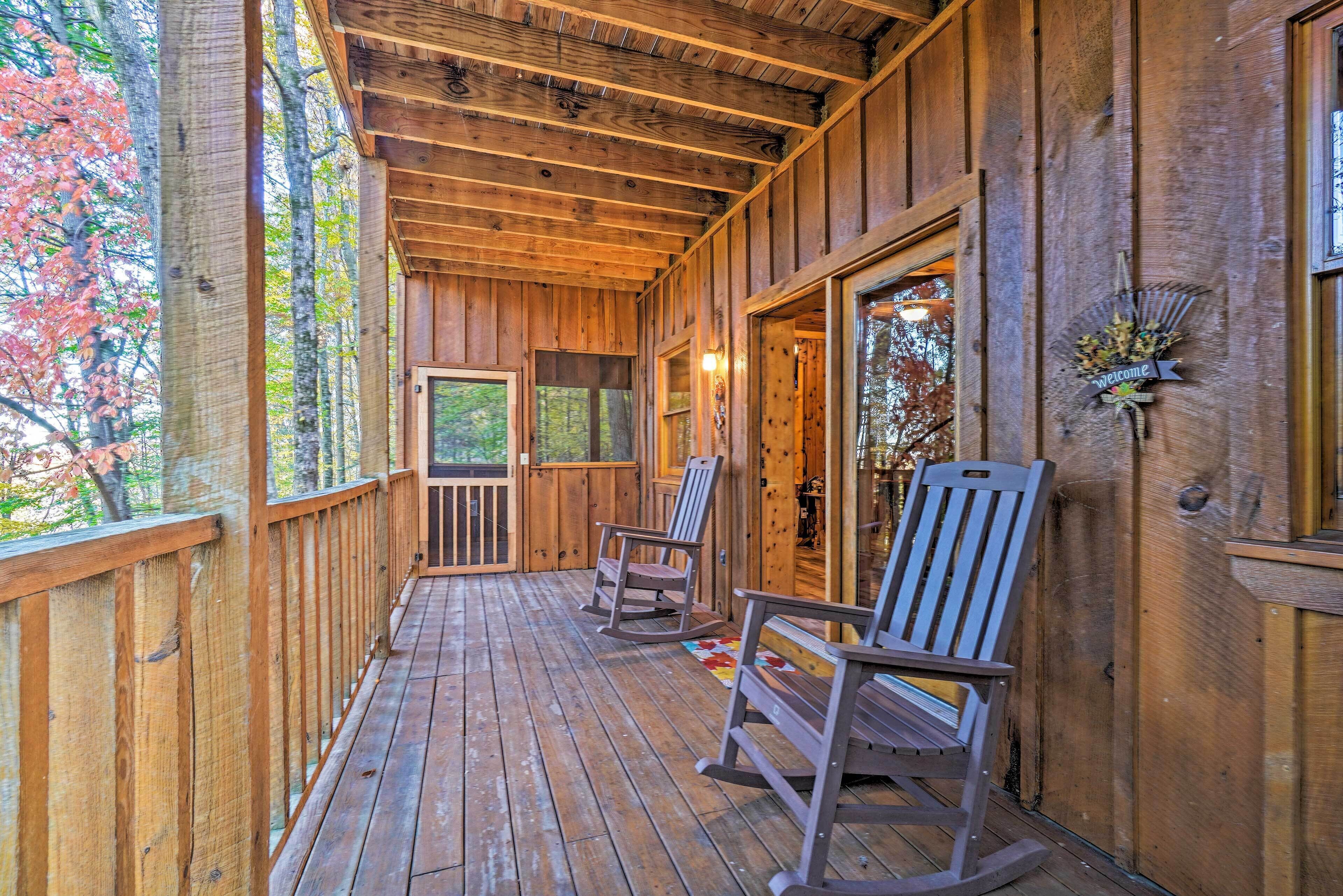 A wooden porch with rocking chairs, a wooden door, and a welcome sign.