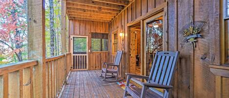 A wooden porch with rocking chairs, a wooden door, and a welcome sign.