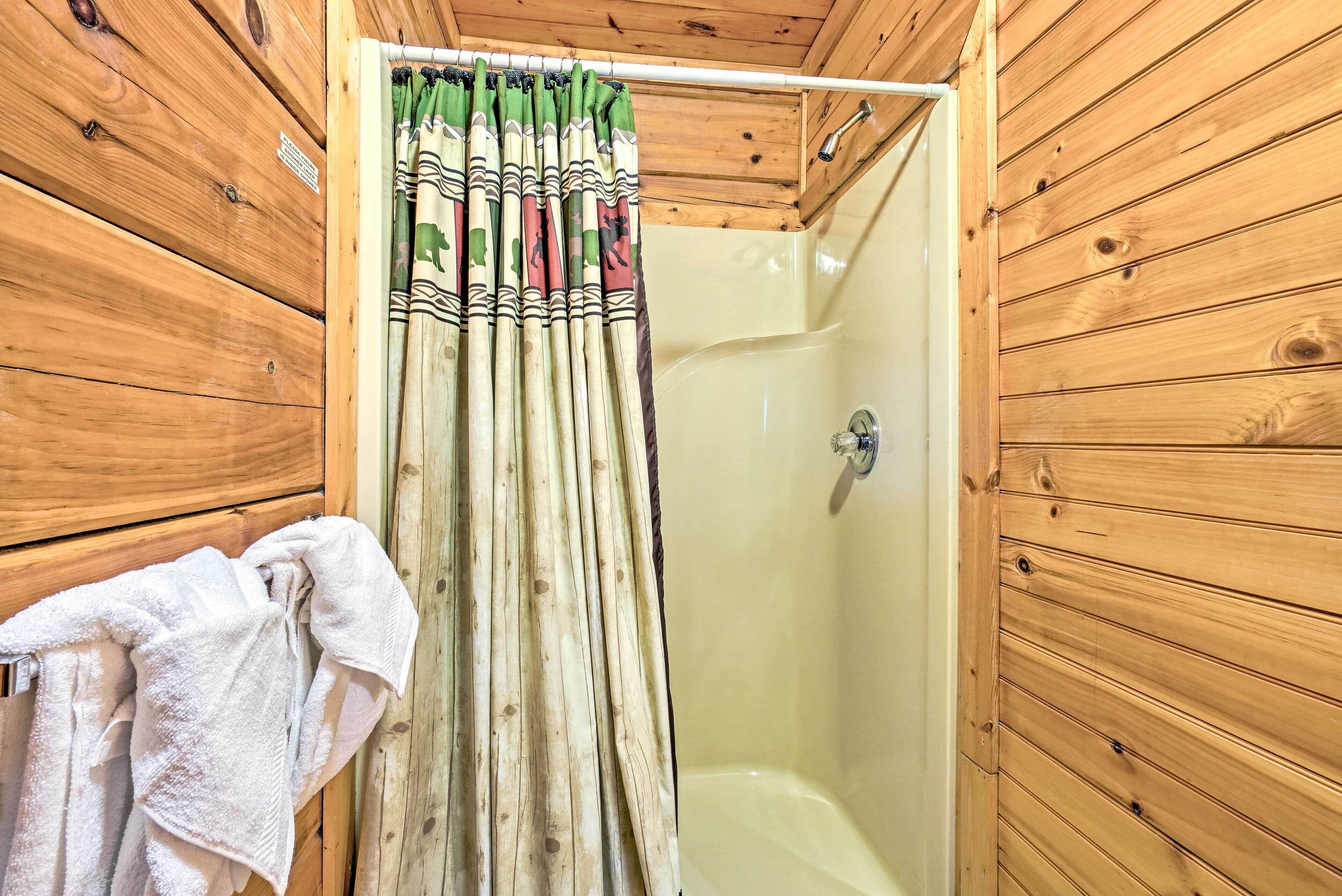 A wooden cabin bathroom with a shower and a towel rack.