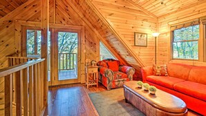 Ein Holzinnenraum mit einem roten Sofa, einem Holztisch und einem Deckenventilator.