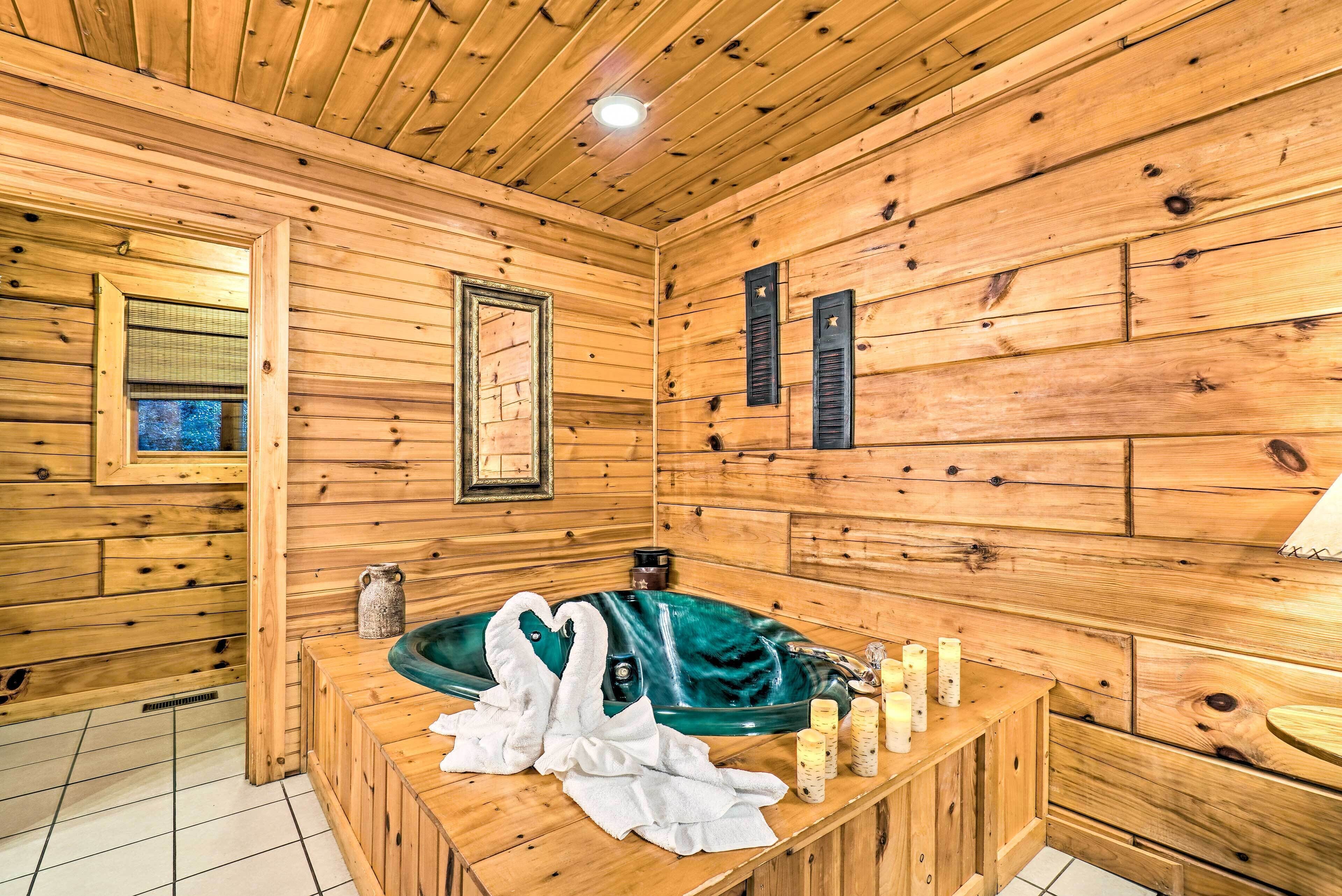 Ein Holzblockhaus-Interieur mit einer großen Badewanne, Handtüchern, Kerzen und einem Spiegel.