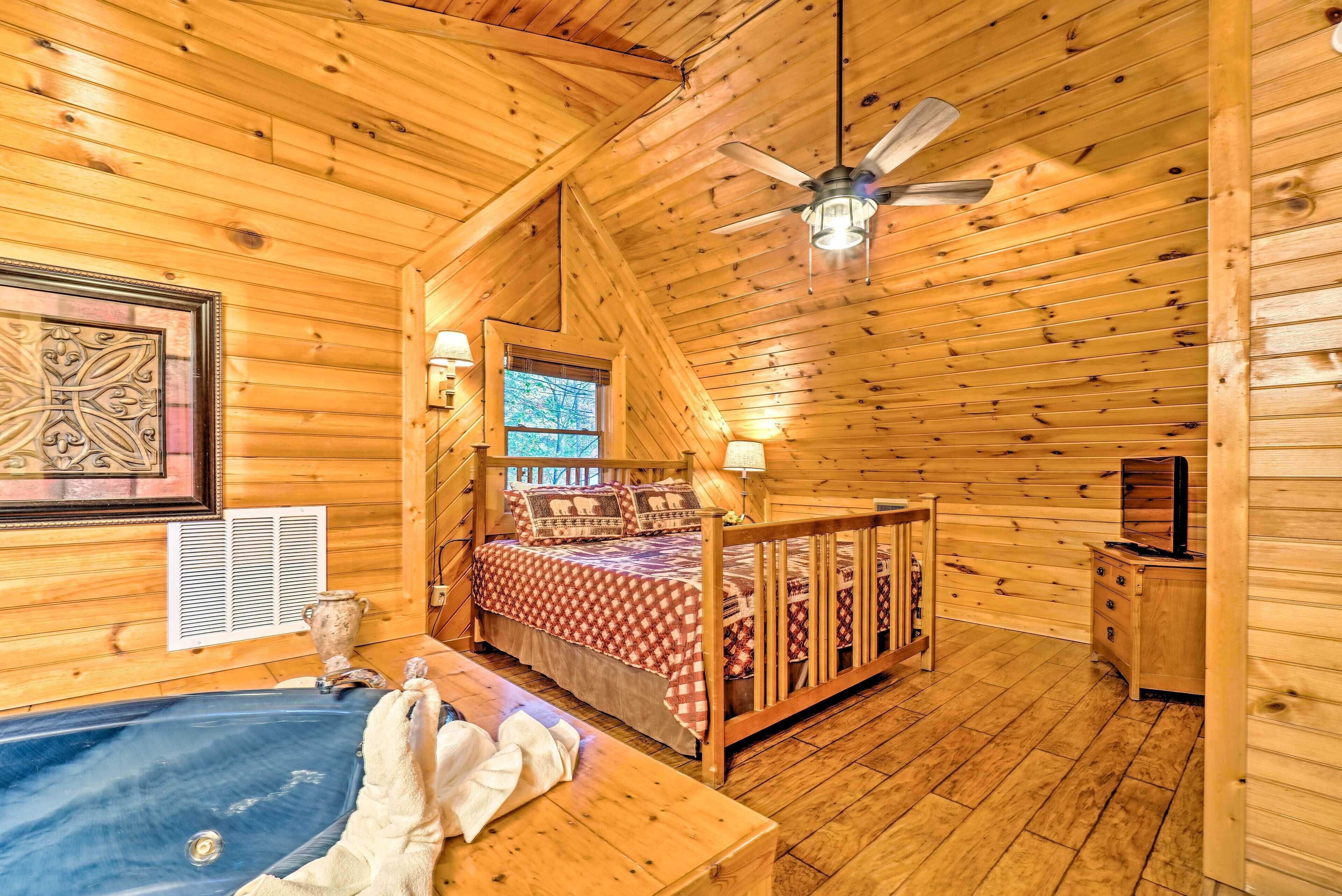 Un dormitorio de cabaña de madera acogedor con una cama, un escritorio pequeño, un tocador y una bañera.