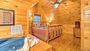 Ein gemütliches Schlafzimmer in einer Holzhütte mit einem Bett, einem kleinen Schreibtisch, einem Schminktisch und einer Badewanne.