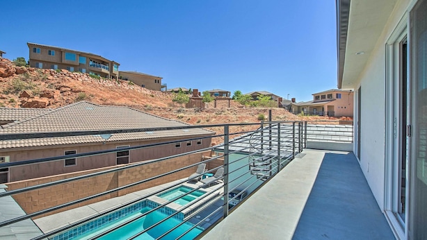 Ett bostadsområde med en swimmingpool, en balkong med glasräcke och hus med en ökenliknande bakgrund.