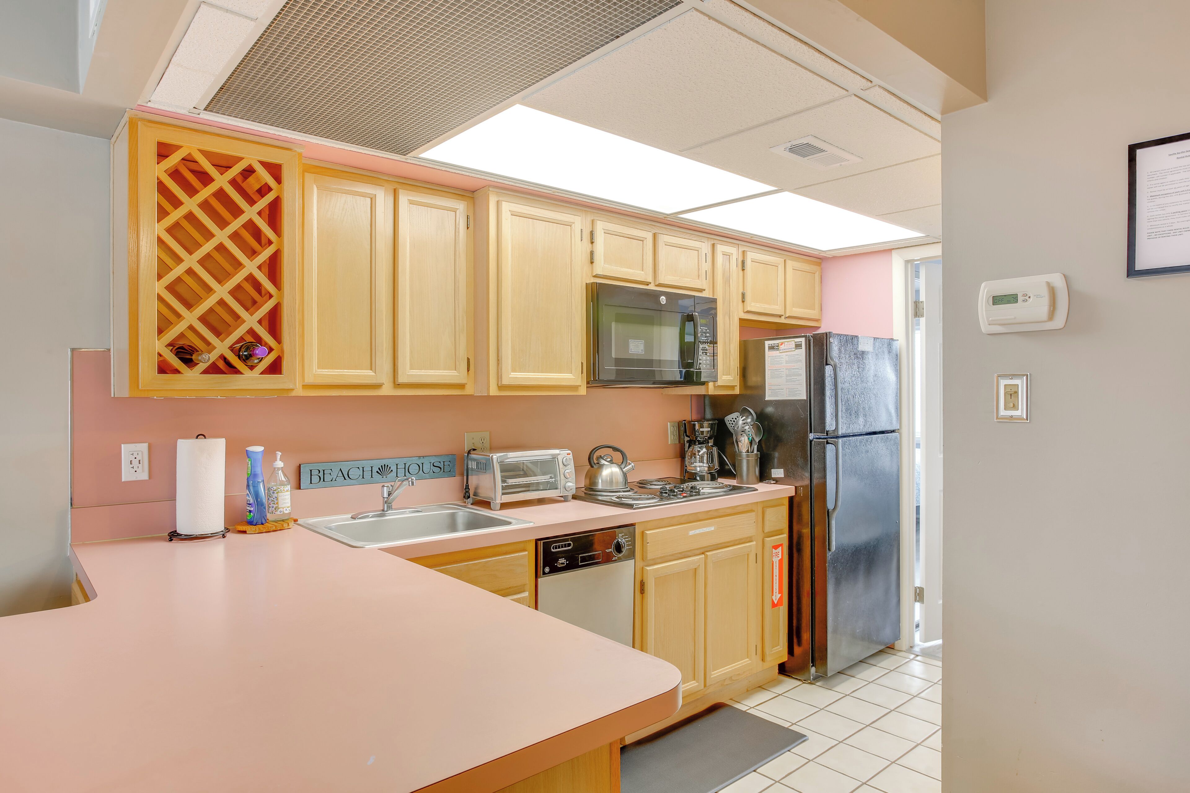 A kitchen with wooden cabinets, a microwave, a toaster, and a refrigerator.