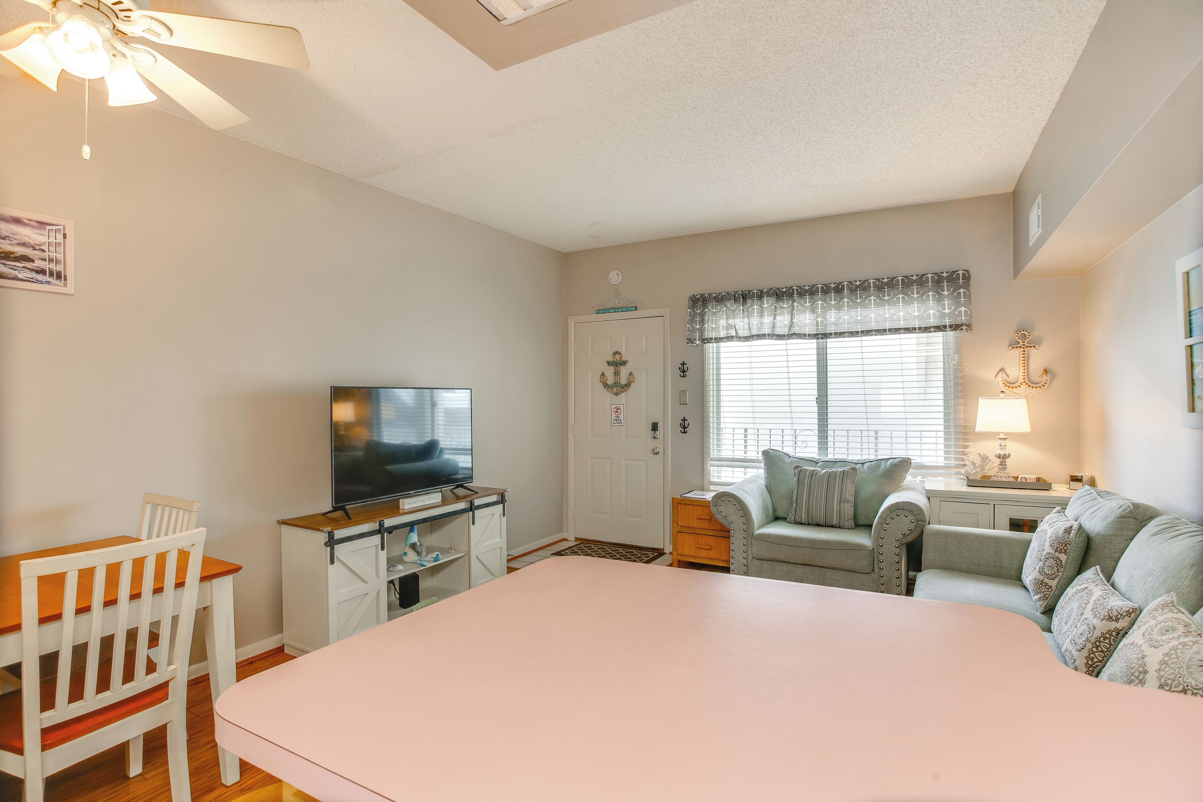 A bedroom with a bed, a TV, a desk, a chair, a sofa, and a window with curtains.
