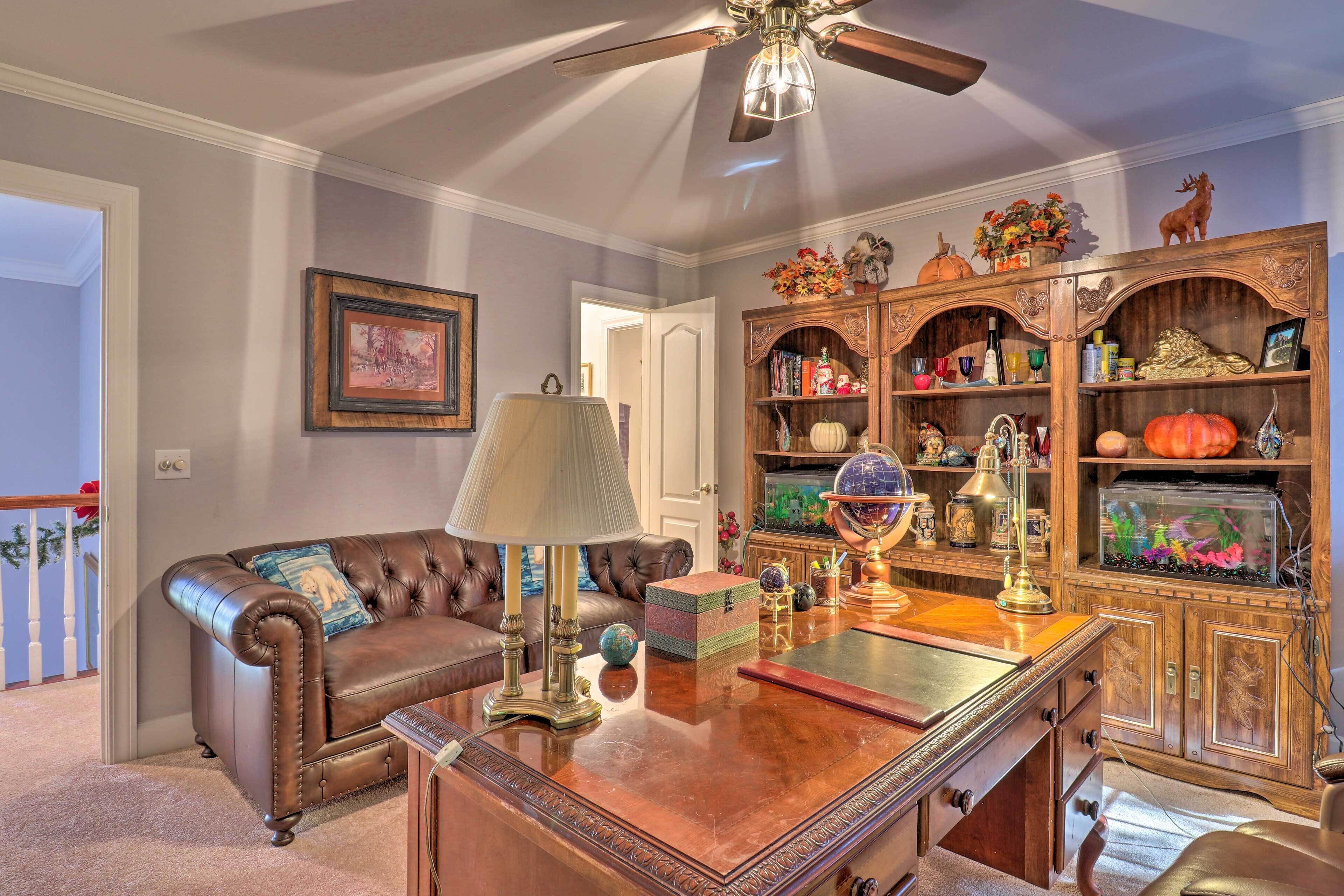 A living room with a leather sofa, a wooden coffee table, a globe, and a bookshelf filled with various items.