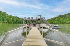 A wooden dock extending into a lake with boats docked at the end.
