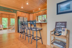 A spacious kitchen with wooden cabinets, a refrigerator, and a dining area with chairs.
