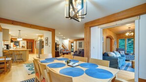 A spacious dining area with a large wooden table and blue placemats, surrounded by wooden chairs. - Lakefront Paradise Near Okemo & Killington (Mount Holly)