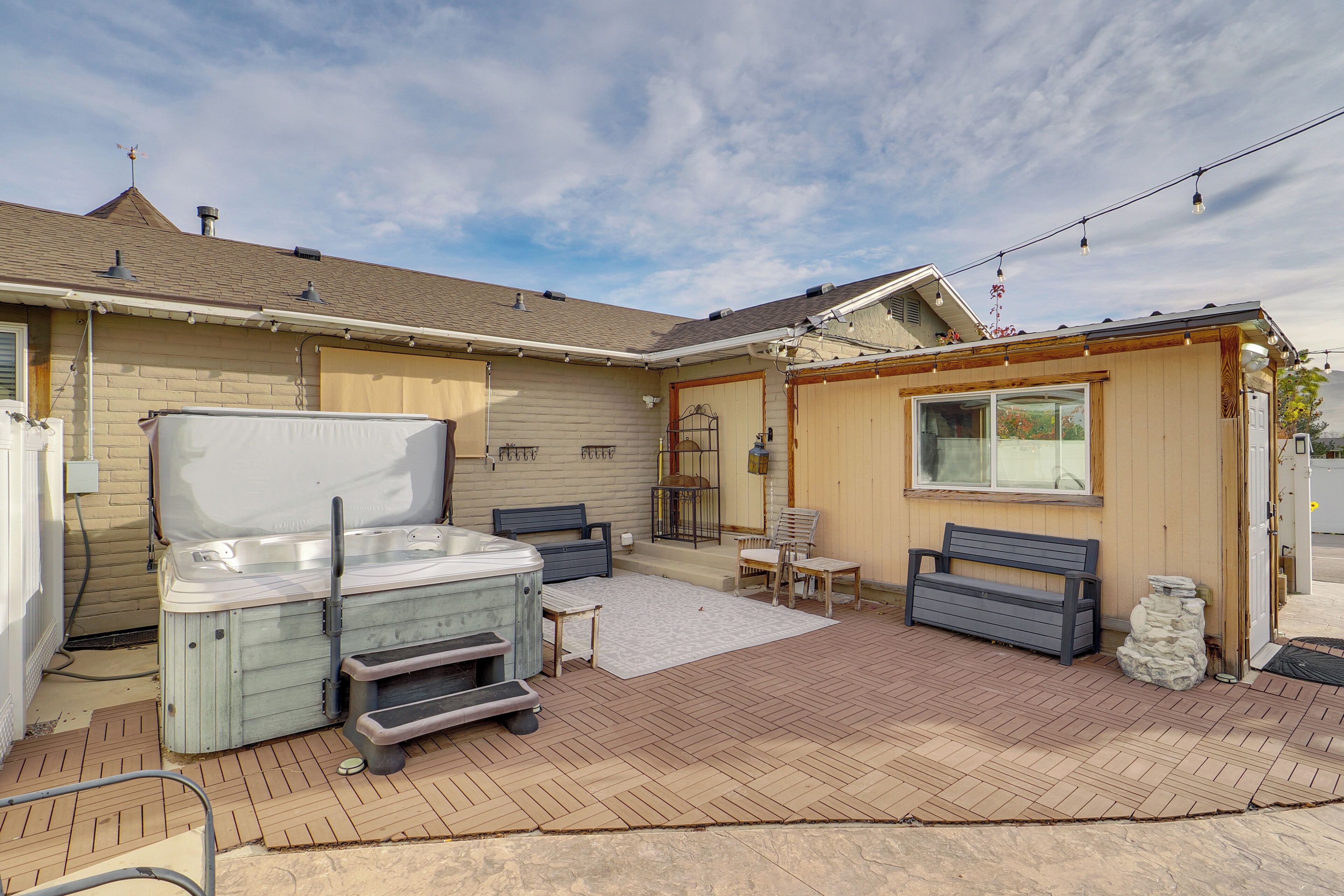 A backyard with a hot tub, outdoor seating, and a pergola.