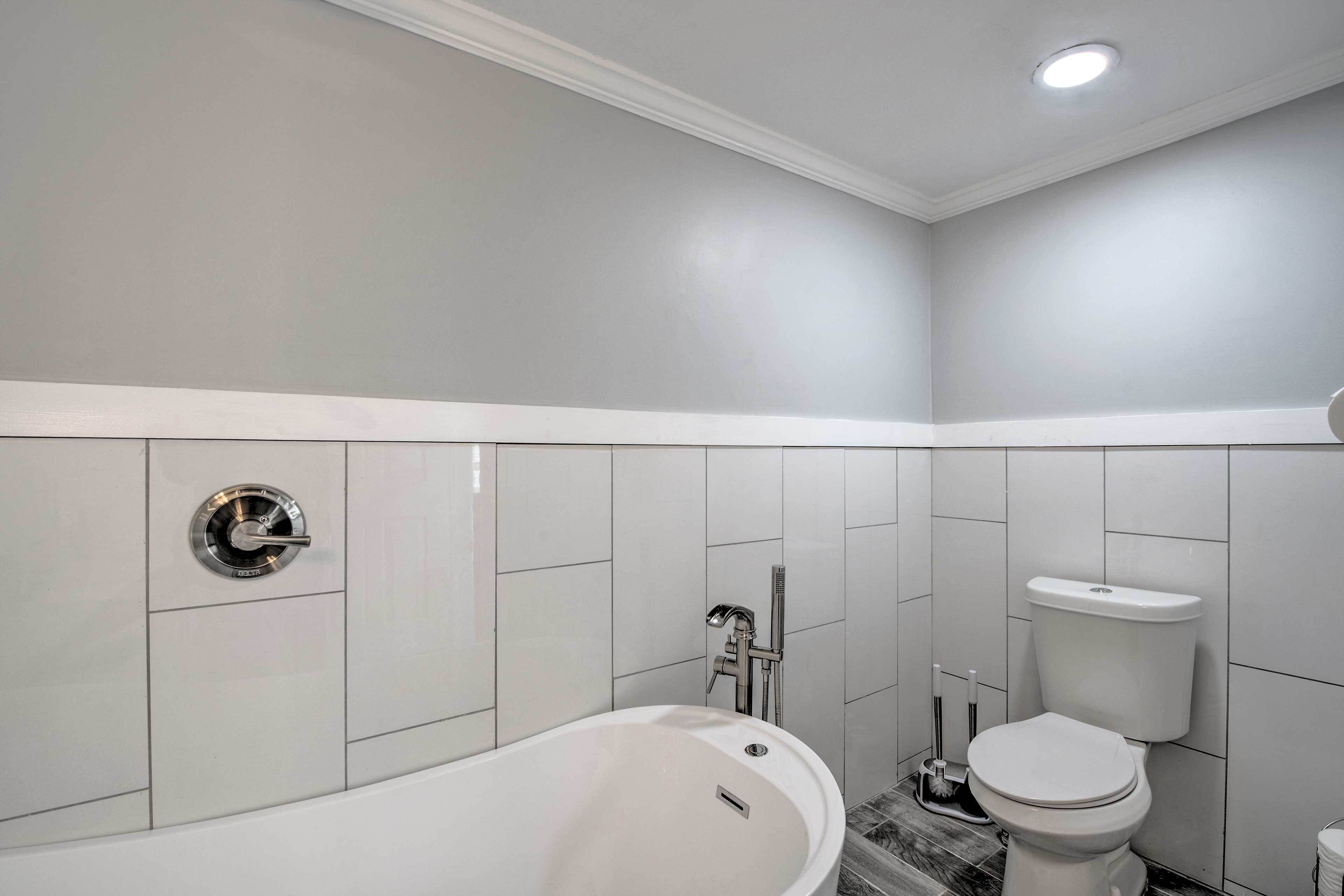 A modern bathroom with a bathtub, toilet, and a shower area.