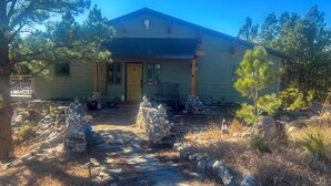 A rustic cabin with a stone pathway leading to the entrance, surrounded by pine trees and a clear blue sky. - Hermosa Home w/ Black Hills View, Gas Grill & Deck (Hermosa)