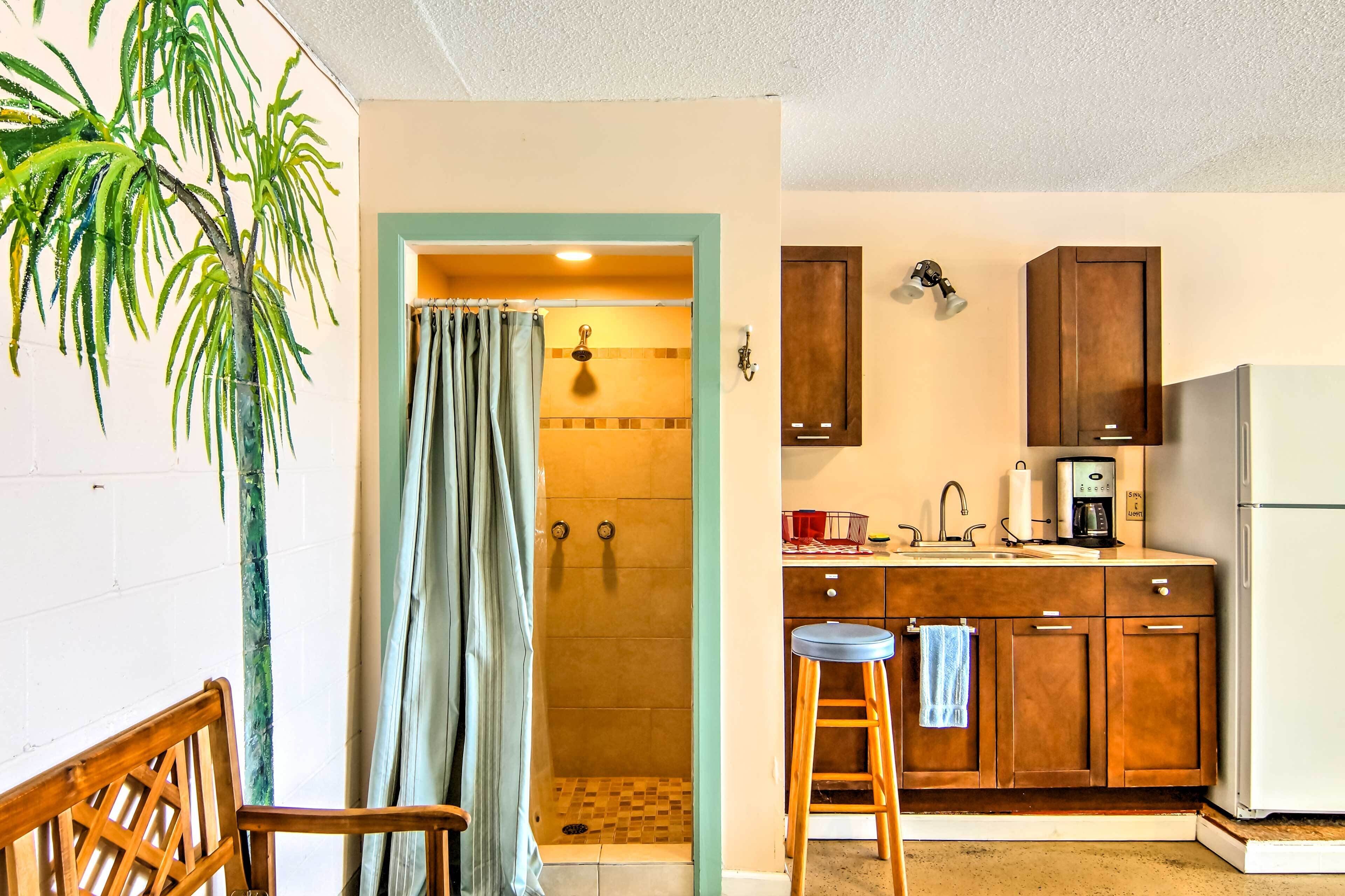 A small kitchen with wooden cabinets, a sink, and a shower area.