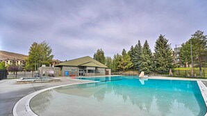 A swimming pool with a surrounding deck, a small building with a green roof, and tall trees in the background. - All-season Sun Valley Retreat w/ Deck & Grill (Sun Valley)