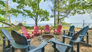 A beachside seating area with Adirondack chairs and a fire pit. - Waterfront Cheboygan Home w/ Fire Pit (Cheboygan)