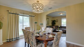 A dining area with a wooden table, patterned chairs, and a chandelier.