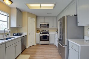 A modern kitchen with white cabinets, stainless steel appliances, and a large window providing natural light. - 16 Mi to Dtwn Dallas: Spacious Home w/ Yard! (Cedar Hill)