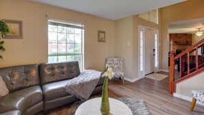 A living room with a leather sofa, a round coffee table with a vase, a patterned armchair, and a staircase leading to another room.