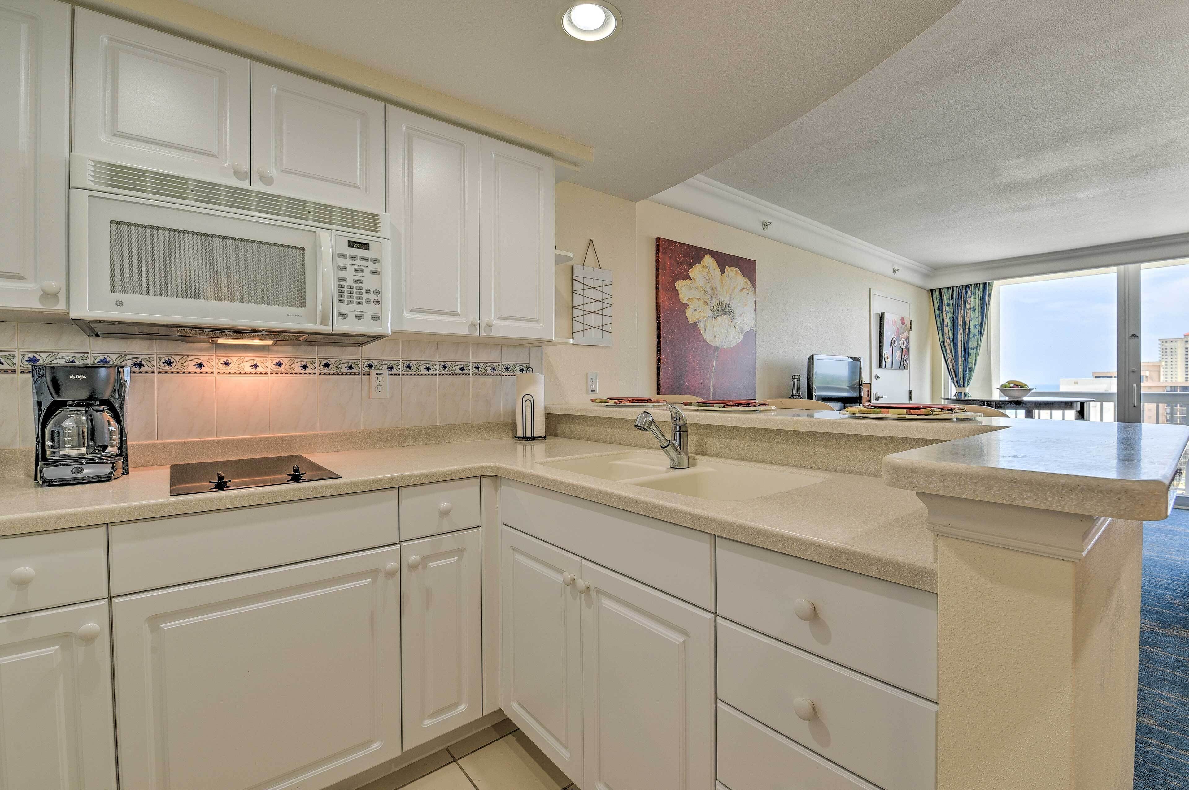 A modern kitchen with white cabinets, a built-in microwave, and a coffee maker.