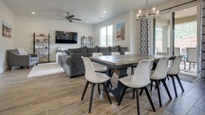 A spacious living room with a dining area, a ceiling fan, and a large window. - Sleek + Modern Home Rental Near Red Cliffs! (Washington)