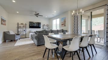 A spacious living room with a dining area, a ceiling fan, and a large window.