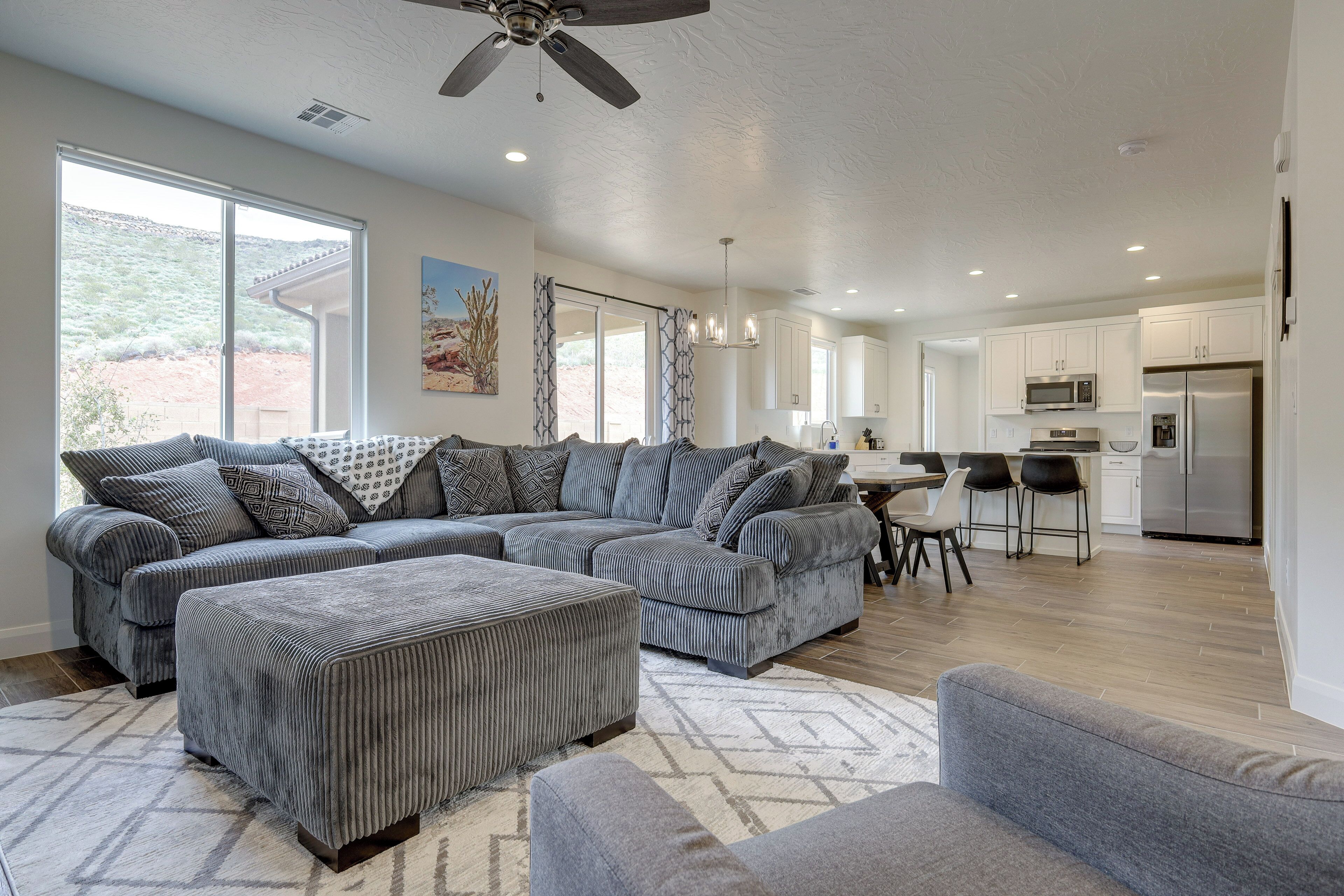A spacious living room with a large sectional sofa, ottoman, and a dining area with chairs.