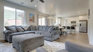 A spacious living room with a large sectional sofa, ottoman, and a dining area with chairs.