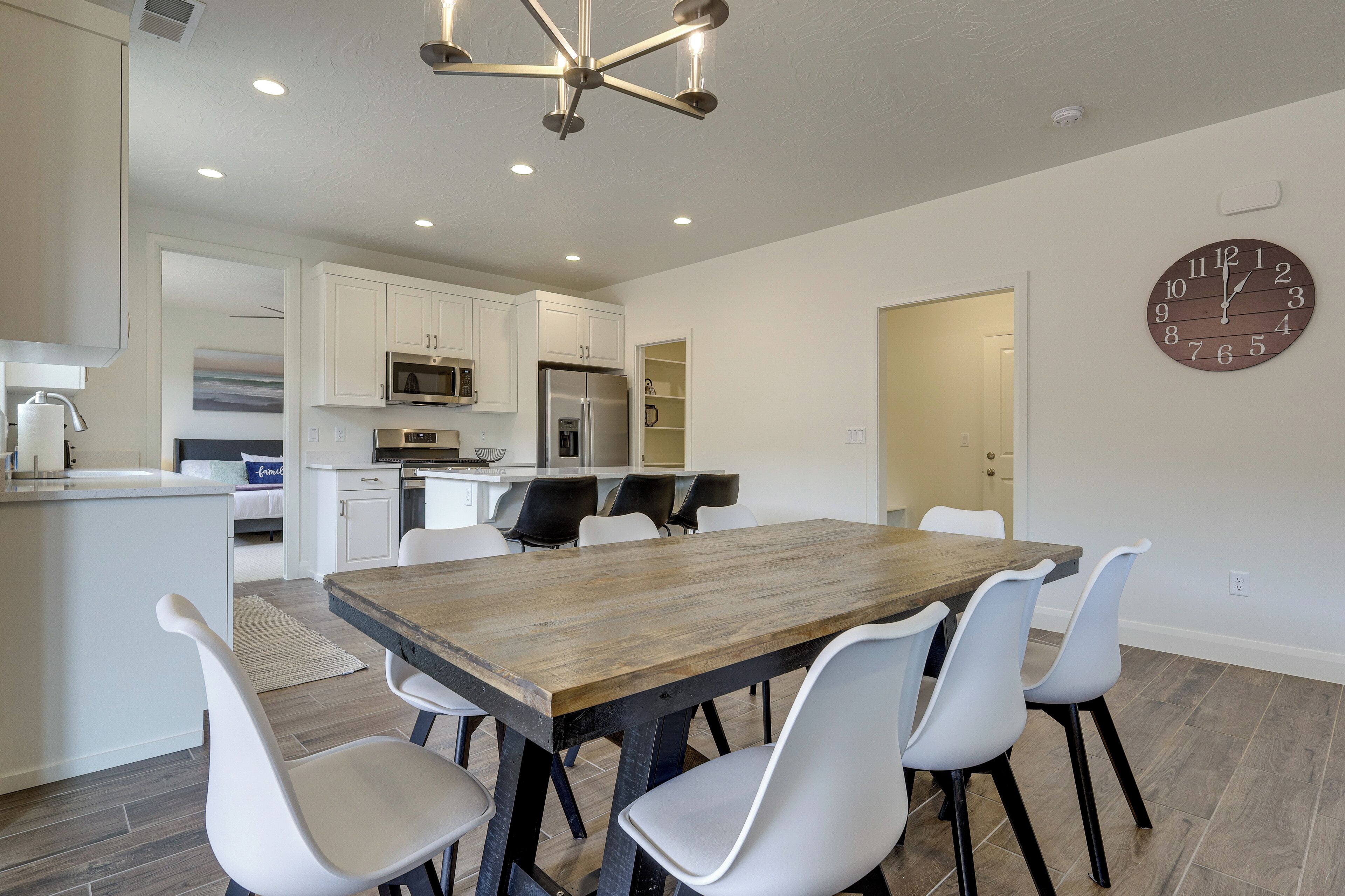 A modern kitchen with white cabinetry, a wooden dining table, and white chairs.