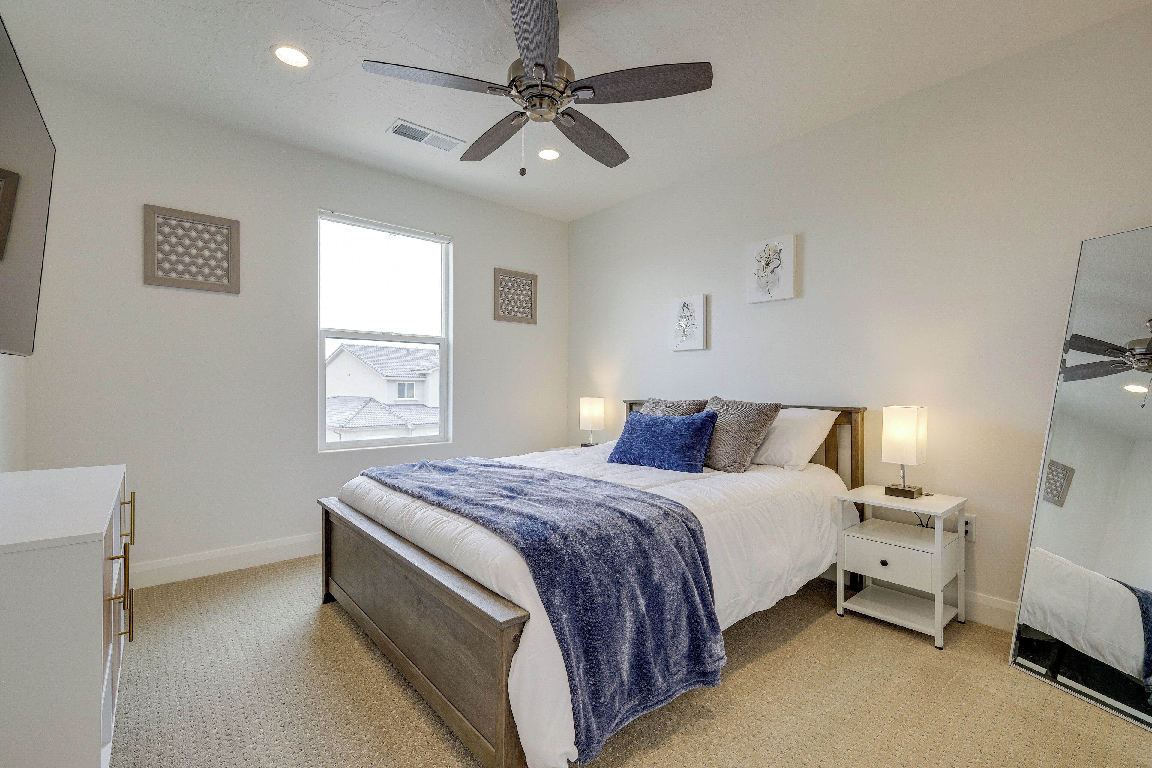 A bedroom with a bed, nightstands, a ceiling fan, and a window.