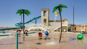 A water park area with a slide, water jets, and palm trees. - Sleek + Modern Home Rental Near Red Cliffs! (Washington)