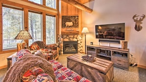 A cozy living room with a fireplace, comfortable seating, a television, and a stone wall. - Klamath Falls Cabin Retreat w/ Deck & Grill! (Klamath Falls)