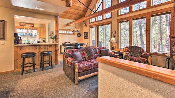 A cozy interior with a wooden ceiling, large windows, a bar area, and a seating area with a patterned sofa. - Klamath Falls Cabin Retreat w/ Deck & Grill! (Klamath Falls)