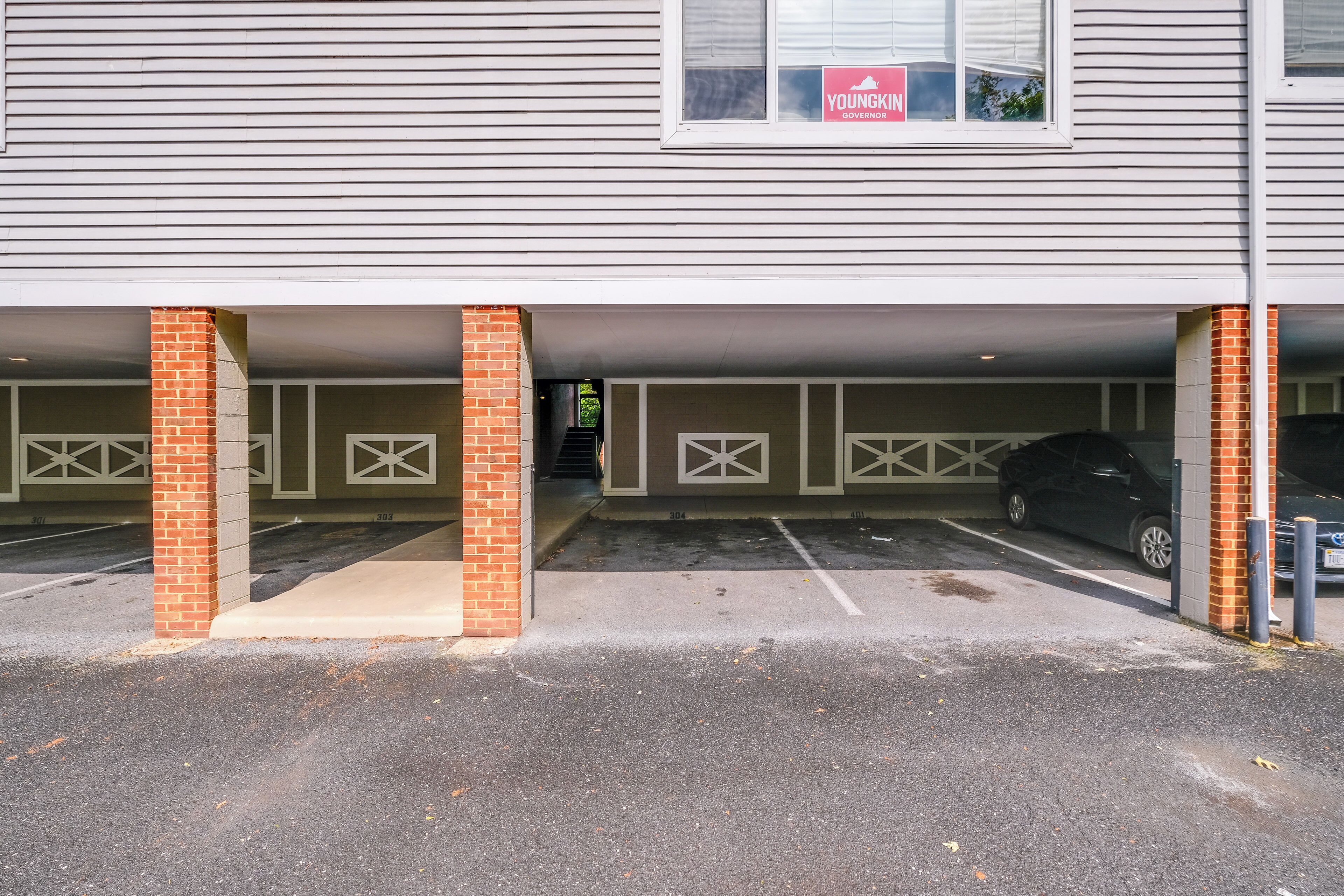 Un parking souterrain avec de nombreuses places de stationnement, un pilier en briques et une affiche faisant la promotion de Youngkin comme gouverneur.