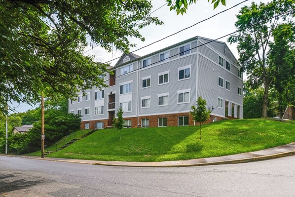 A multi-story residential building with a brick base and white upper floors, featuring a central staircase and a small front yard. - Walk to W&l: Lexington Condo Near Shops & Dining (Lexington)