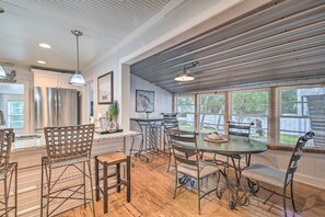 Une cuisine spacieuse dotée d’un grand îlot central, d’appareils électroménagers en acier inoxydable et d’un coin repas avec une table ronde et des chaises en métal.