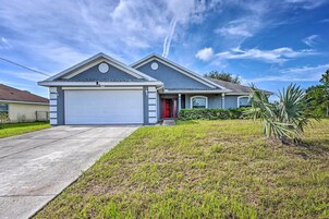 A two-story house with a garage, a red door, and a well-maintained lawn.