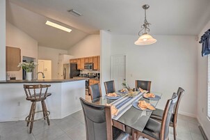 A modern kitchen with a central island, wooden chairs, and a dining table set for four.