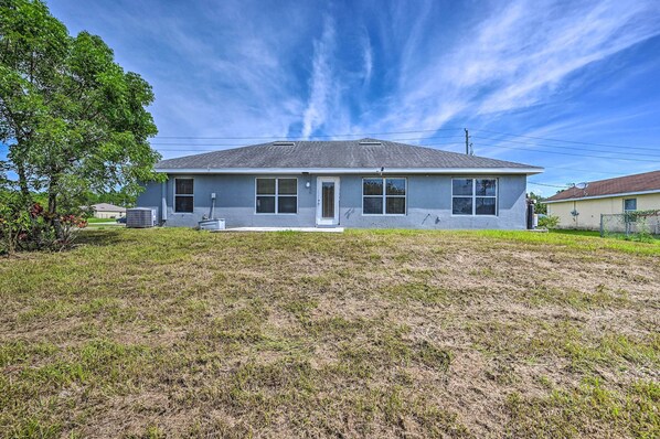 A single-story house with a flat roof, a front porch, and a small front yard. - Ranch-style Lehigh Acres House With Big Backyard! (Lehigh Acres)
