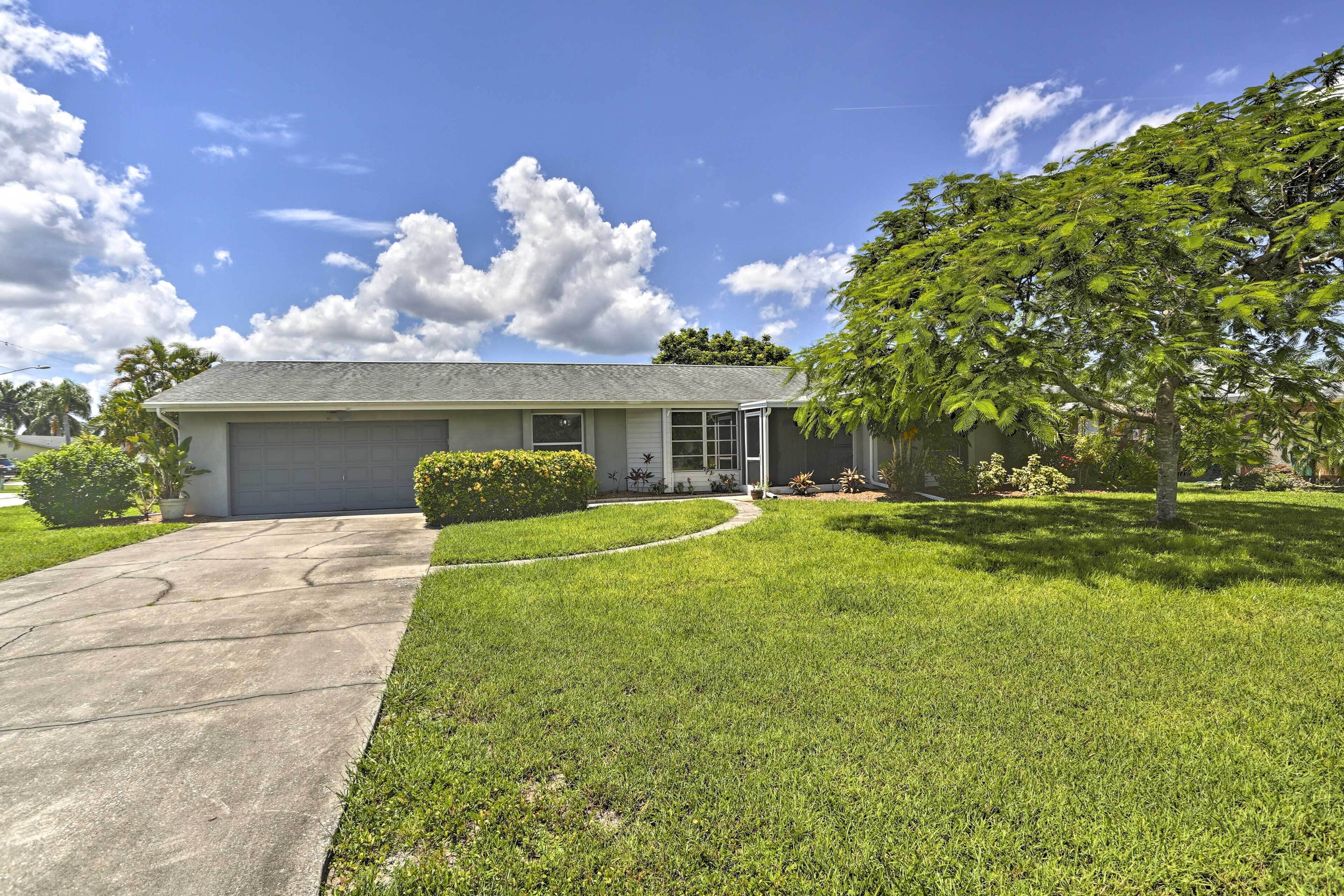 A single-story house with a garage, a well-maintained lawn, and a large tree in the front yard.