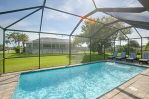 Ein Schwimmbecken mit überdachtem Bereich, klarem, blauem Wasser und einem Haus im Hintergrund.