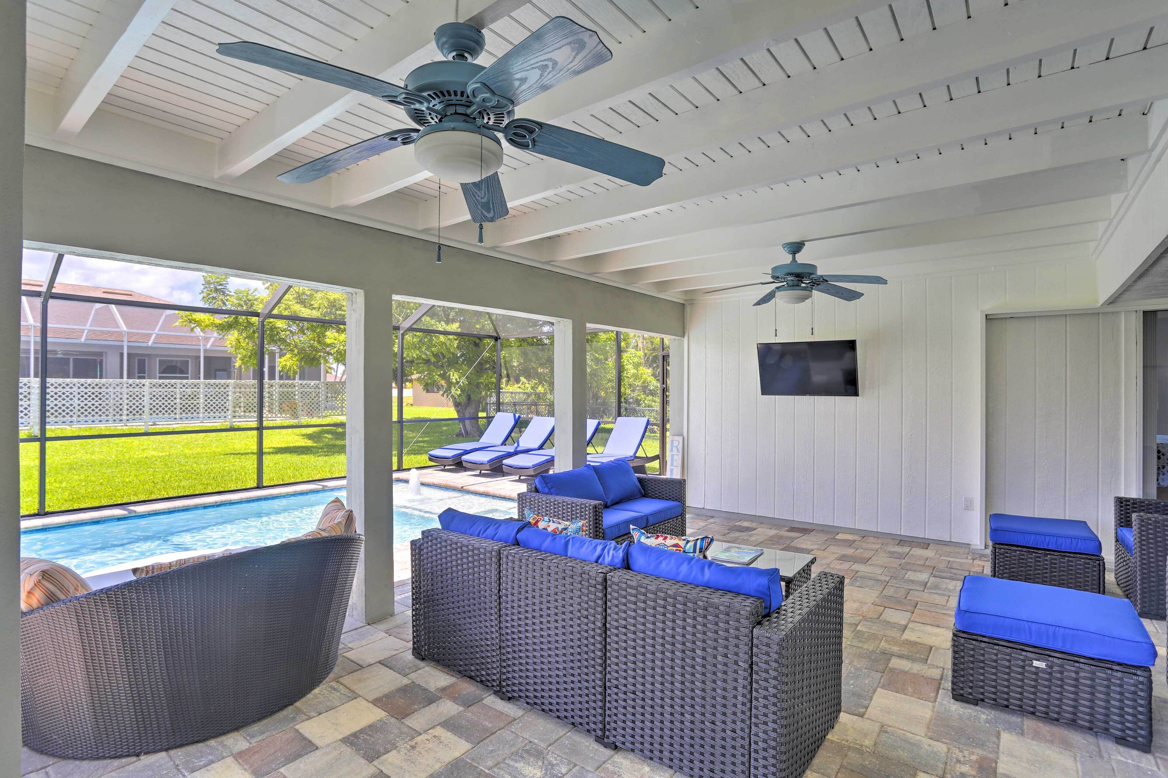 A covered outdoor area with wicker furniture, ceiling fans, and a view of a swimming pool.